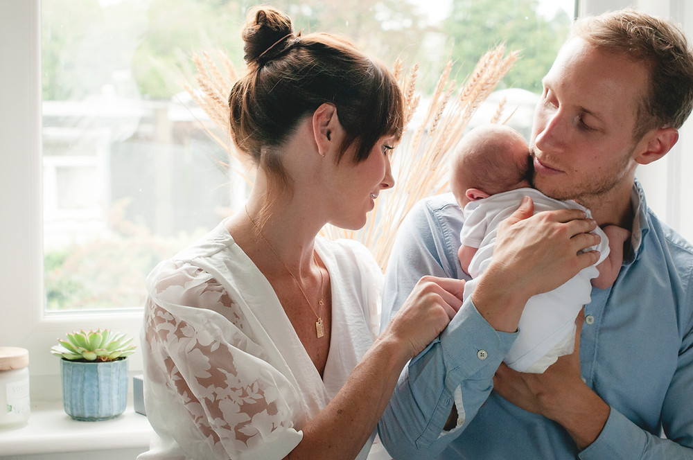 couple with newborn baby boy in window