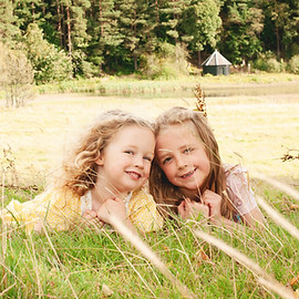 sisters lying in the grass during an outdoor family photo session in midlothian