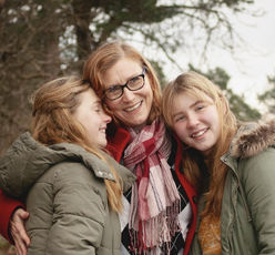 mother with teenage daughters smiling during a winter photo session outdoors