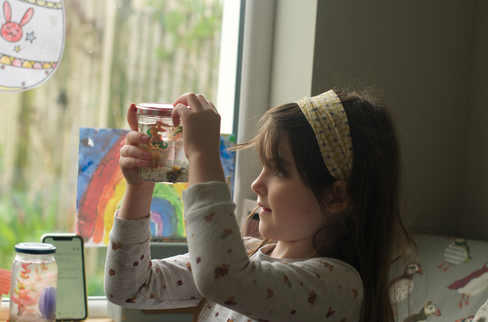 a little girl holding up a jar