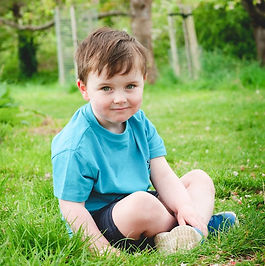 little boy sitting on grass