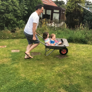 dad pushing children in wheelbarrow in candid family photo