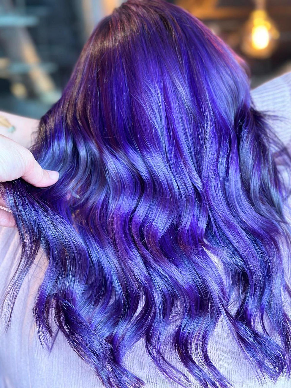 Three-quarter view of glossy freshly coloured hair resting over a salon chair.