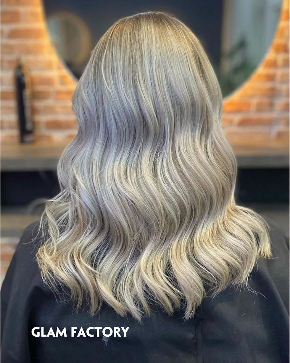 Eye-level view of a stylist applying a conditioning treatment to freshly washed hair.