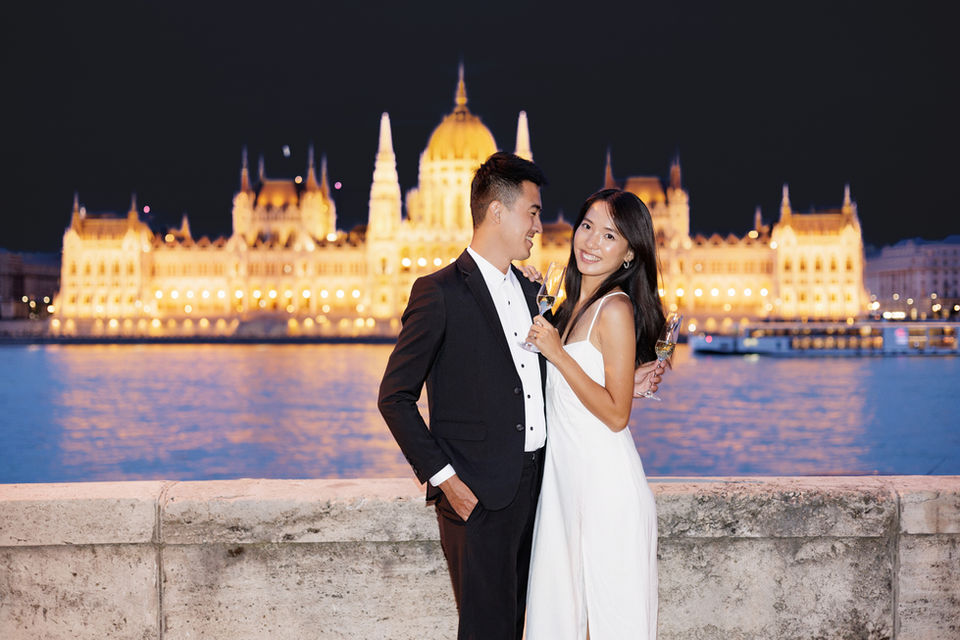 Night portrait of a couple with illuminated Budapest architecture.