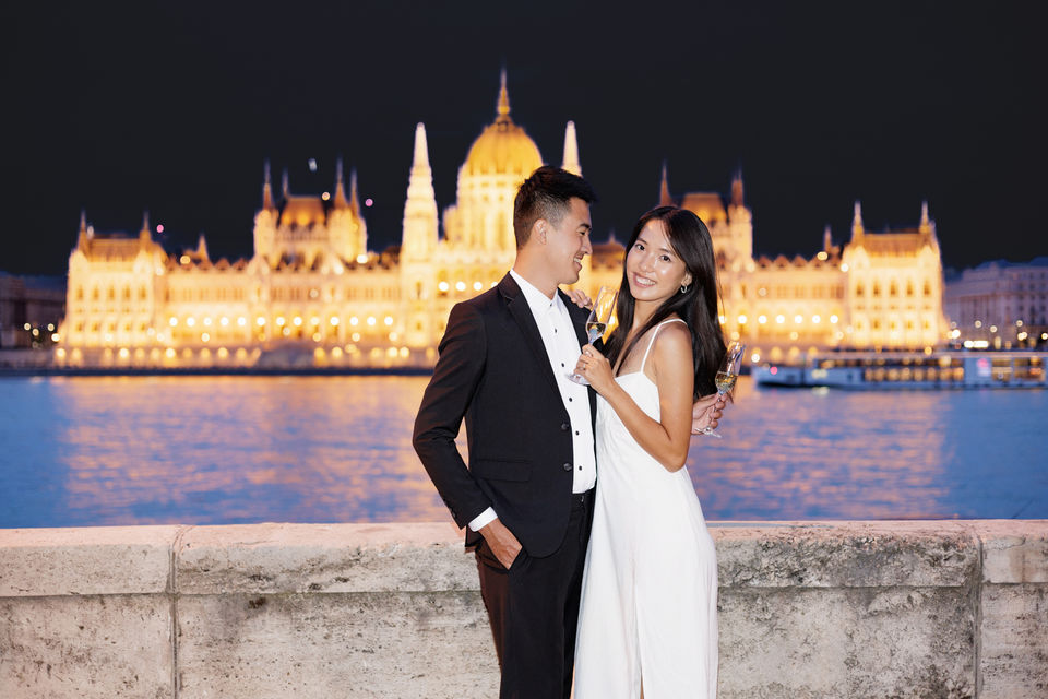 Night portrait of a couple with illuminated Budapest architecture.