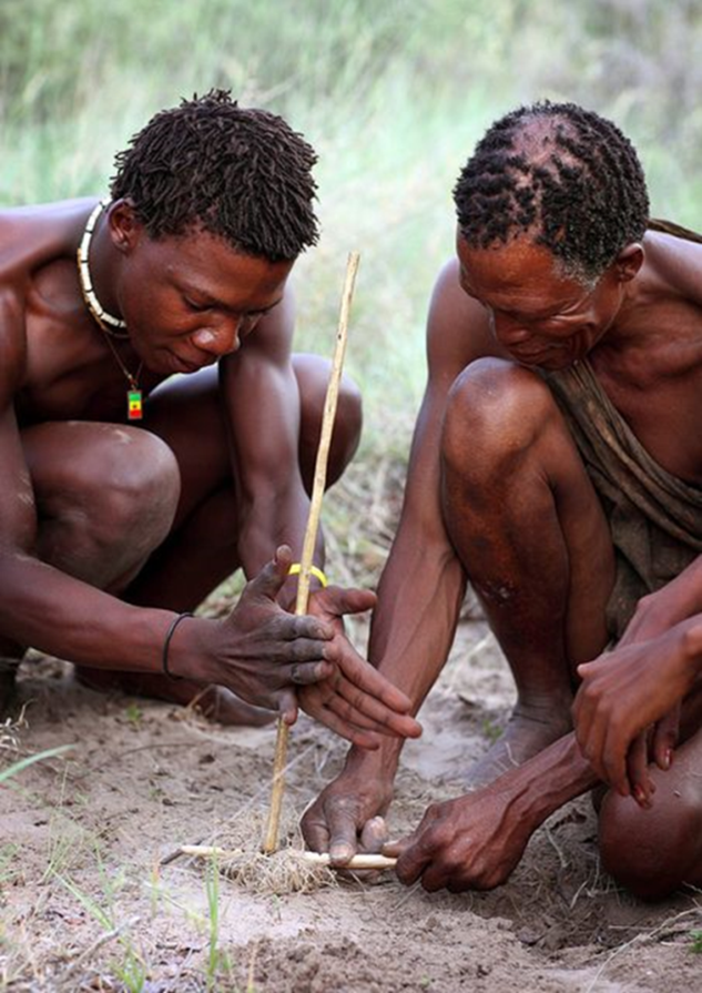 Friction, sand and dried grass are used to make fire with a traditional fire drill