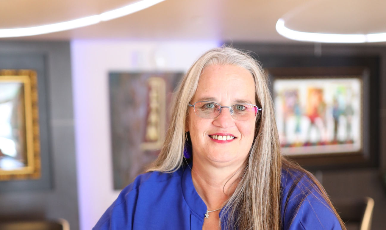 April Pire, community connector and marketing strategist, smiles as she works from her laptop in a bright, welcoming space—ready to help local business owners turn ideas into connection and growth.