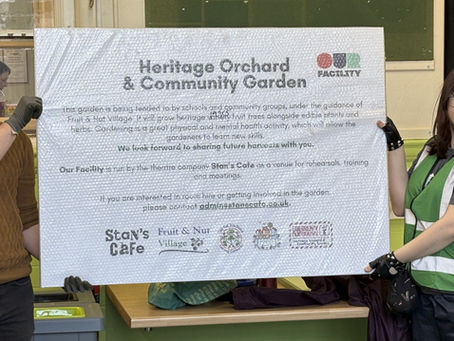 Heritage Orchard & Community Garden sign held up by two participants of the grafting and planting sessions.