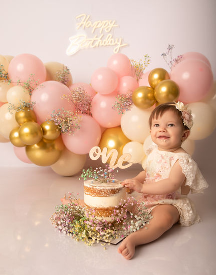 Bebé celebrando su primer cumpleaños en sesión Smash Cake en Madrid con tarta y globos.