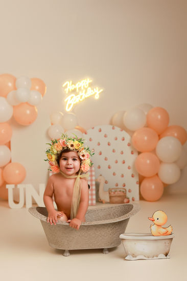 Bebé celebrando su primer cumpleaños en sesión Smash Cake en Madrid con tarta y globos.