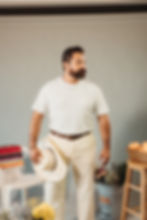 A man standing while wearing a tshirt and holding a sombrero de vaquero in his hand.