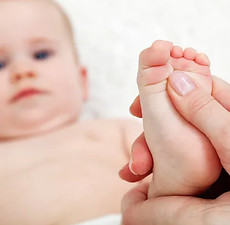 Un bébé, nourrisson, enfant qui se fait masser, lors d'une séance d'ostéopathie 