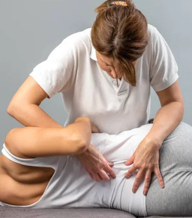 Femme ostéopathe qui fait une consultation d'ostéopathie pour des douleurs dans le bas du dos à une patiente 