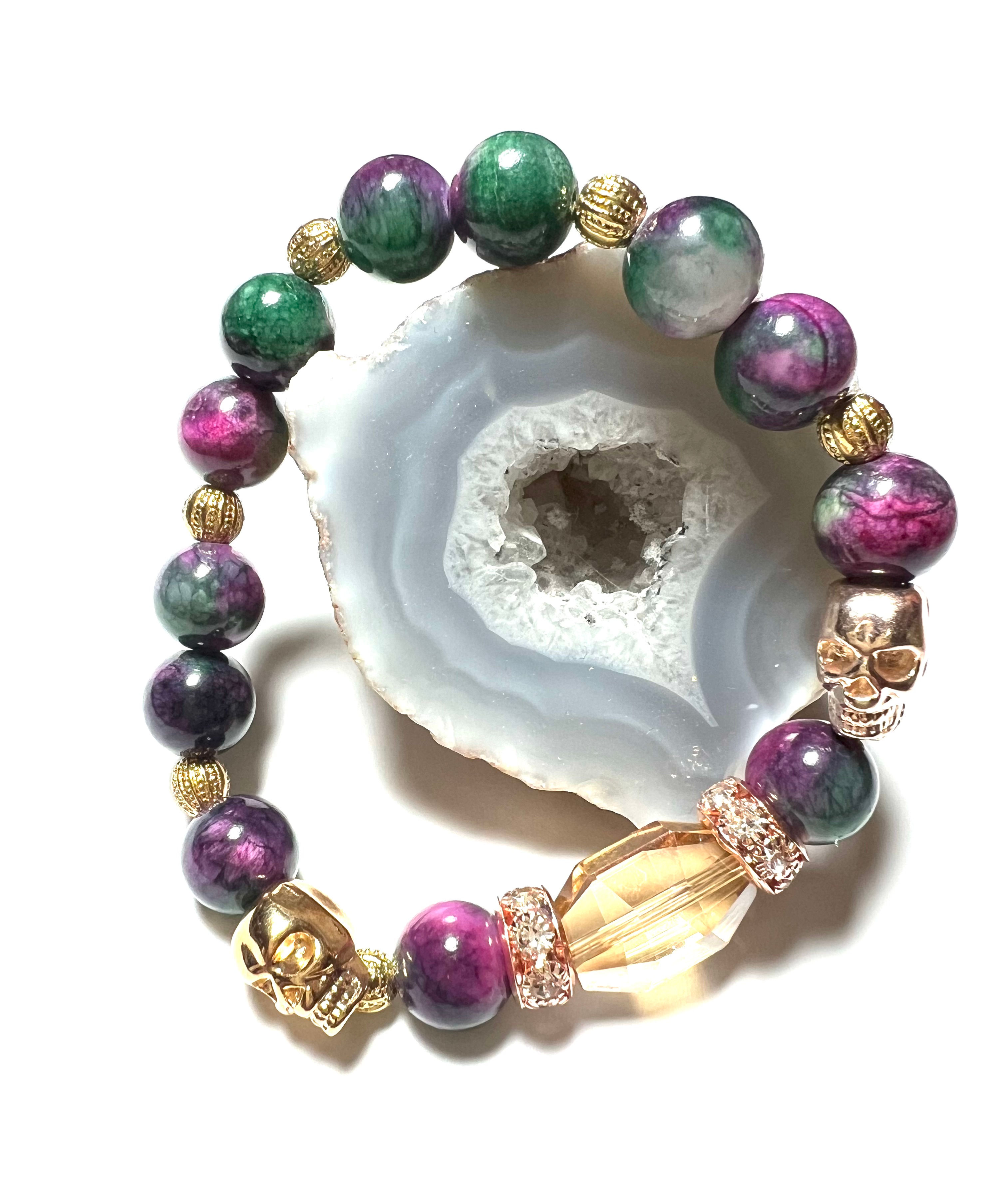 Two metal bronze skulls with purple and green beads with gold tones