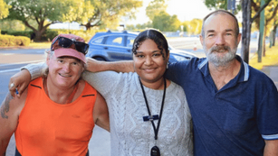 3 people linking arms smiling and facing the camera