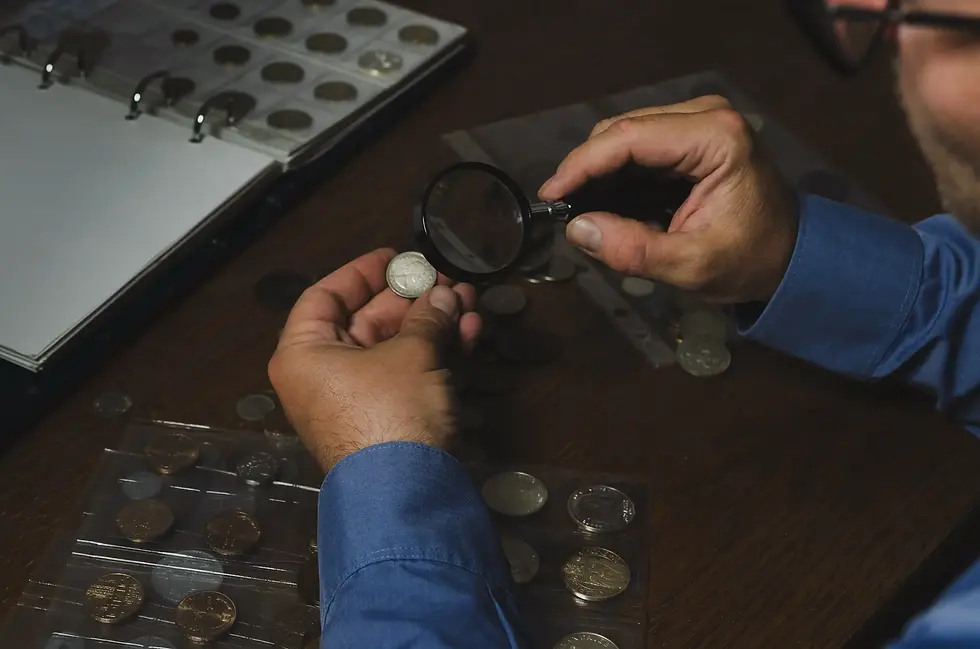 man-with-coins-and-magnifying-glass-at-table-2026-03-13-01-51-25-utc.webp
