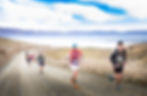 Group of runners stretched out of the spur road section of the Mackenzie Half Marathon. Snowy mountains in the background.
