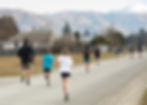 Group of young runners running away from camera up Talbot Road towards the finish line