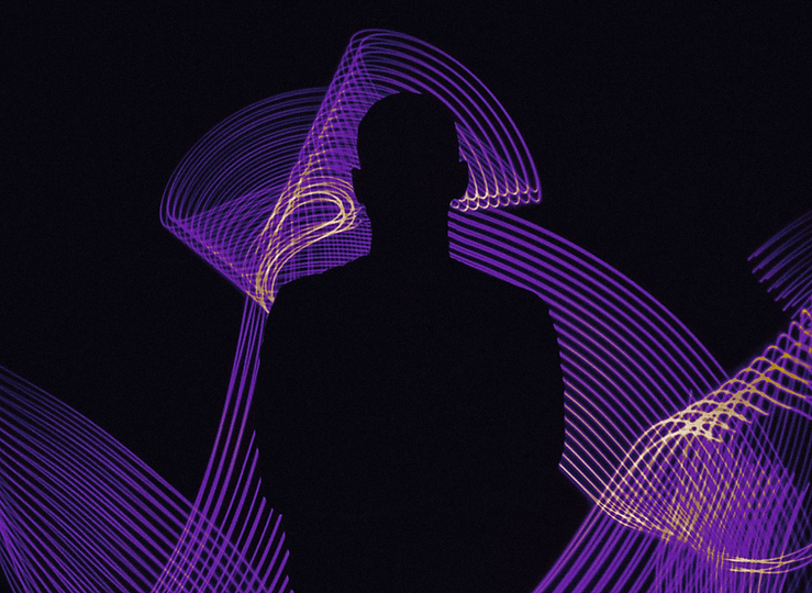 Shadow of a person standing in front of purple, sinuous lines on a black background