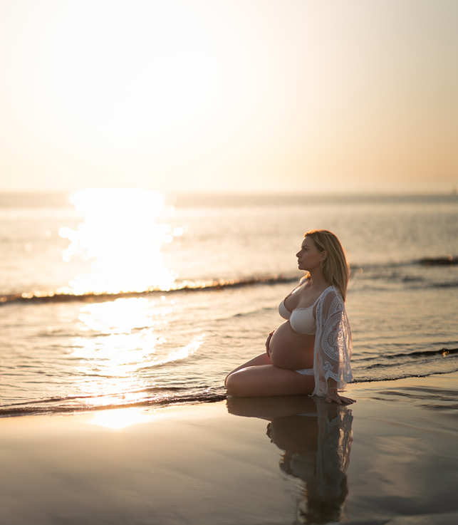 femme enceinte à genou au bord de la mer