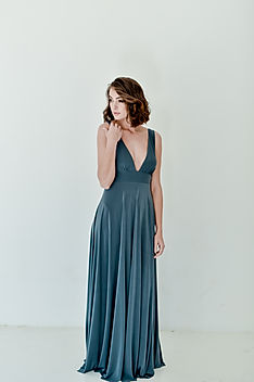 Bridesmaid wearing the Gelique Mekaila Dress in deep teal — a daring, sultry bridesmaid gown featuring a dramatic plunging neckline, open back, fitted midriff yoke, and a flowing full-length skirt. A lightweight, summery design from Gelique Online, perfect for outdoor weddings and chiffon overlay styling.