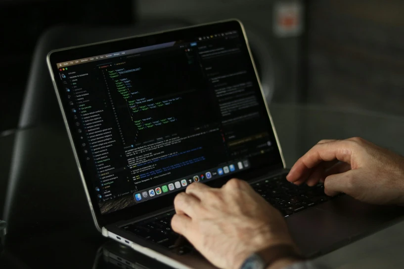 Hands typing code on a laptop