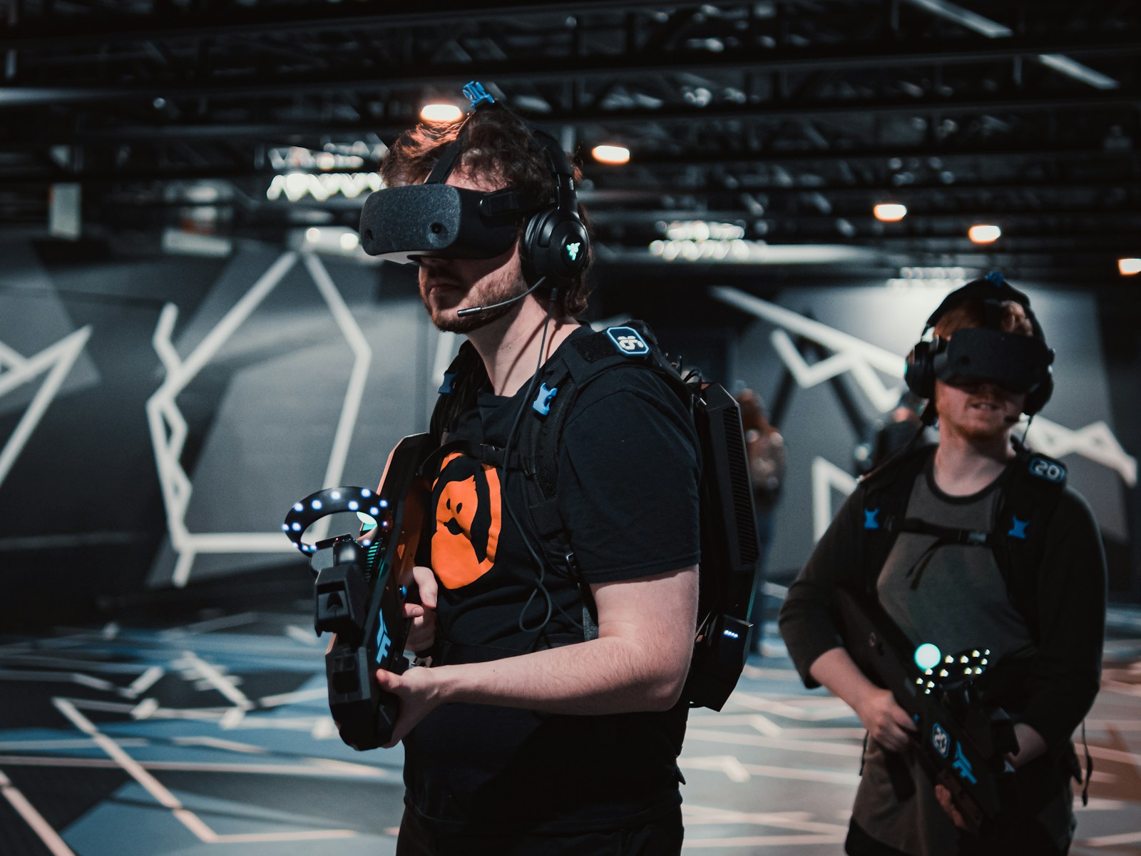 Participants wearing VR headsets and holding tracked controllers in a shared gaming space