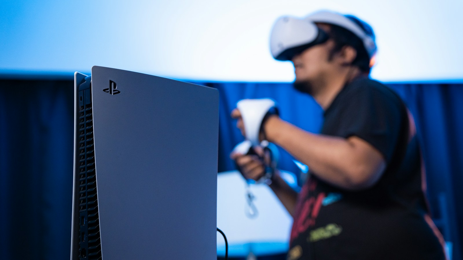 Player using a PlayStation VR2 headset and controllers beside a console