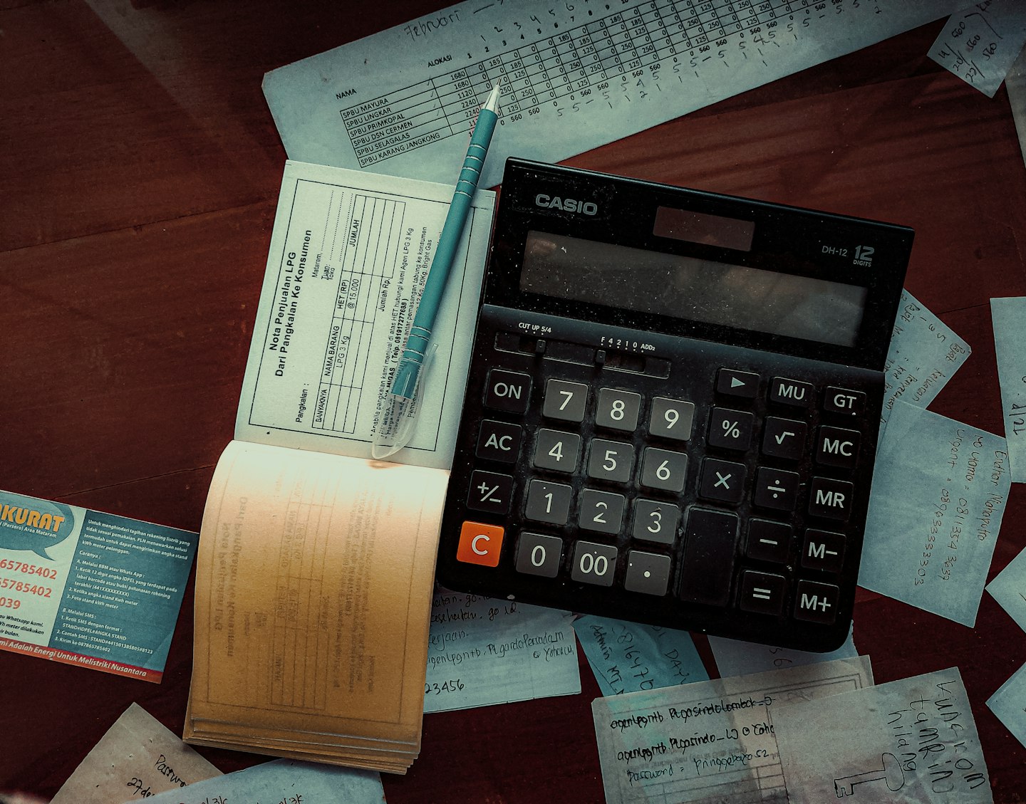 Calculator, pen and business paperwork on a wooden desk