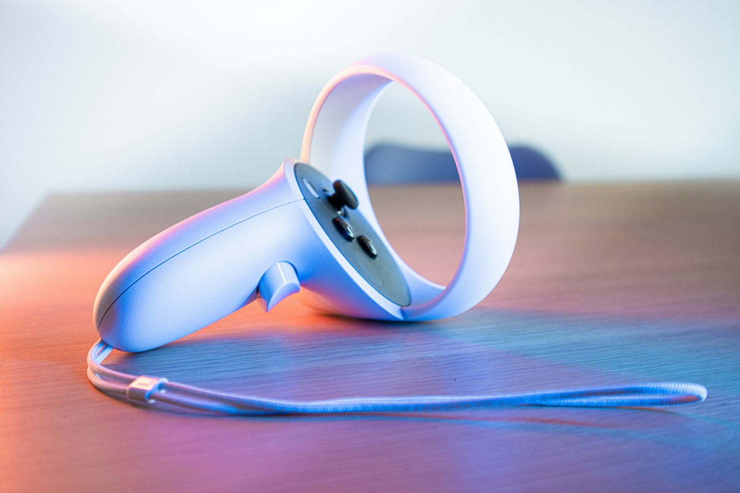 White VR hand controller with wrist strap on a desk