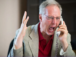 An angry man yelling into a telephone.