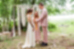 Celebrant wrapping silk ribbons around bride and groom's hands as they 'tie the knot' in a woodland wedding ceremony