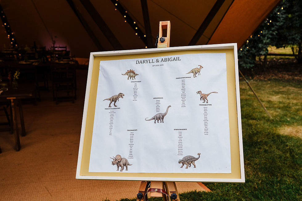 Framed wedding seating chart for Daryll & Abigail with dinosaur illustrations on an easel inside a tent.