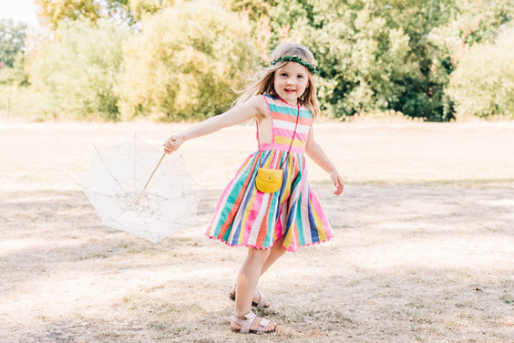 Girl in colourful stripy dress twirling a lace parasol