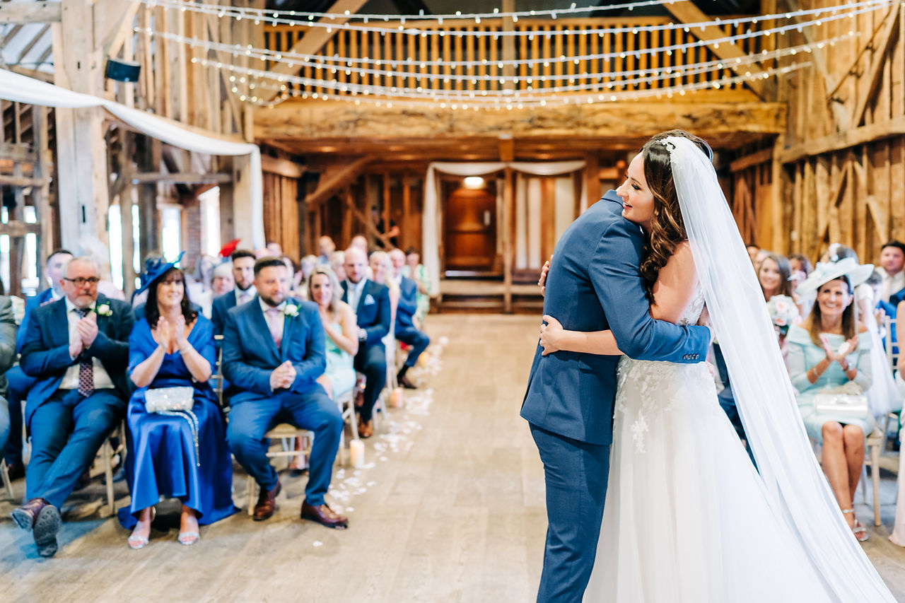 Bride and groom hug after their ceremony while the seated guests applaud