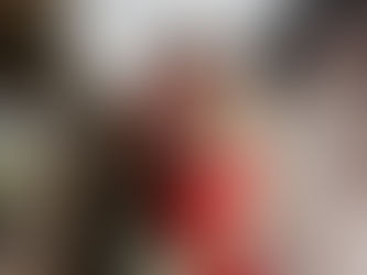 A couple kisses on a vintage train platform, surrounded by steam. She wears a red dress holding flowers; signs read "Ladies Room" and "Booking Office."