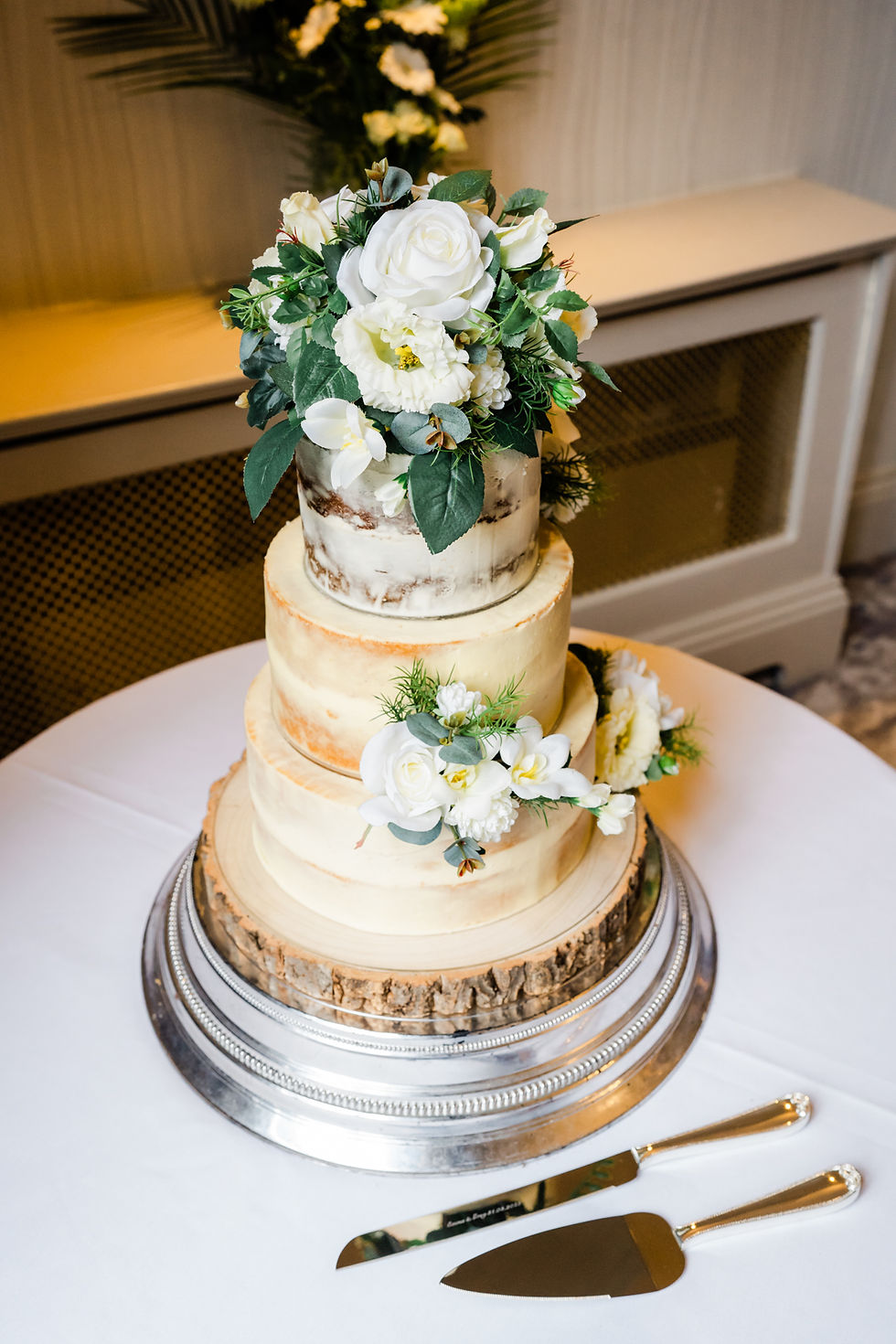 Naked three tier wedding cake decorated with white flowers