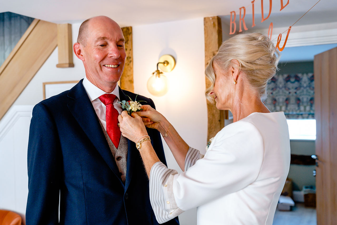 Lady in a cream suit fastening s buttonhole onto a navy suit