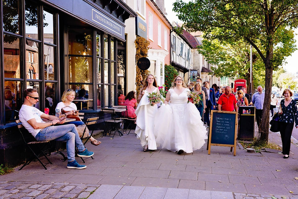 Two brides walking through a busy market town