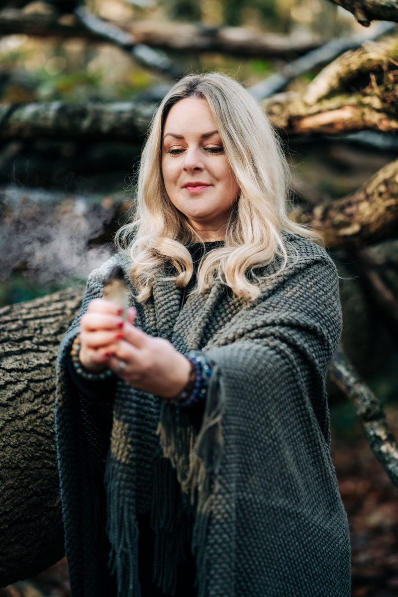 Sophia holding a bunch of lit sage in the woods