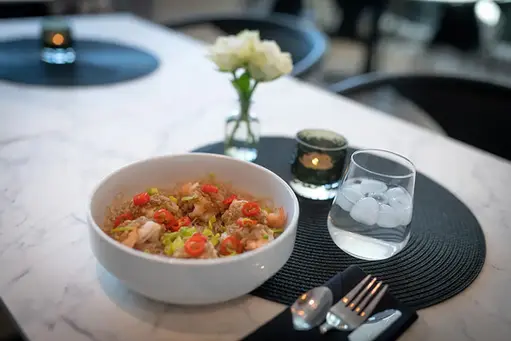 En velsmakende middagsrett med ris, grønnsaker, vann og hvite roser.