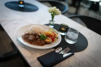 Matrett med ris, kjøtt, salat og vann på marmorbord.