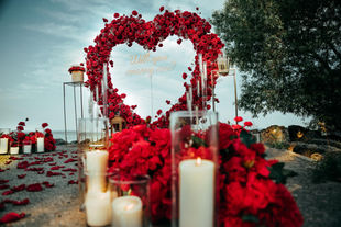 Low shot of a red flower arch with candles in glass and a bouquet of roses