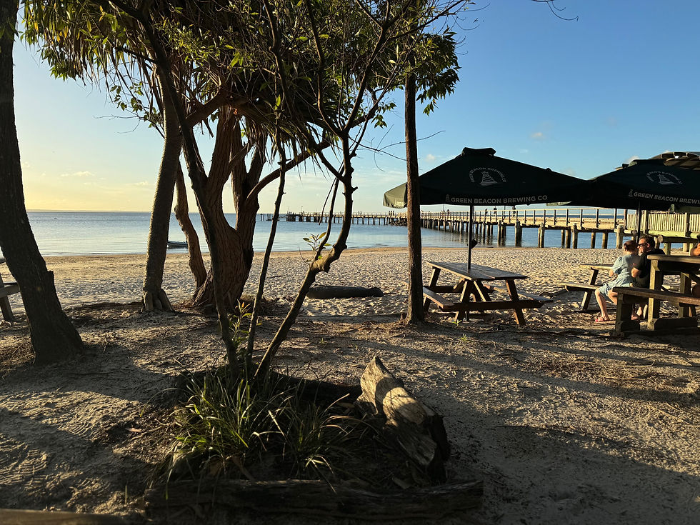 Eye-level view of a wooden deck with outdoor furniture overlooking Fraser Island's forest