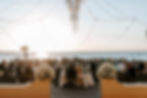 A beautiful wedding reception with guests seated outside overlooking the sunset over the w