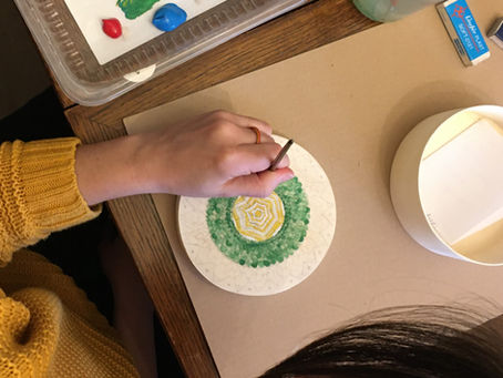 la main d'une femme qui peint un mandala 