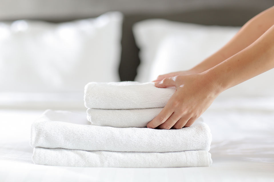 white folded towels being placed on a bed