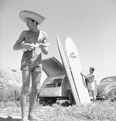 guy playing ukulele and big straw hat on beach
