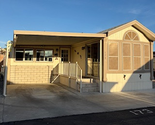 Lot 131 park model home with carport and sunlit windows